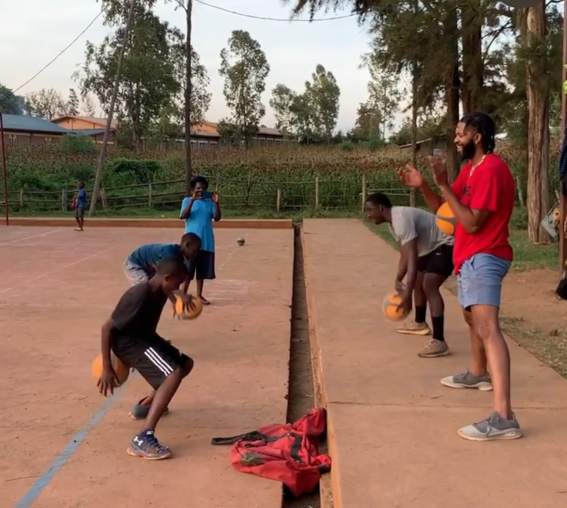 KiShawn working with young people on a basketball court in Rwanda